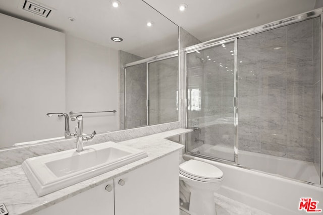 full bathroom featuring vanity, enclosed tub / shower combo, and toilet