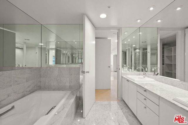 bathroom with vanity and tiled bath