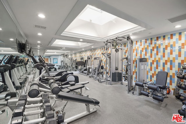 exercise room with a raised ceiling and ornamental molding