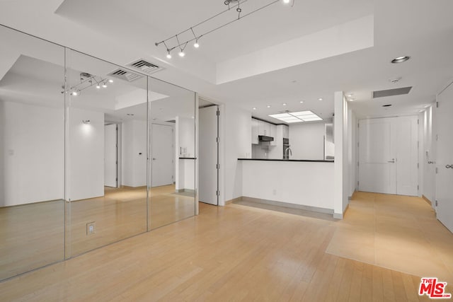 unfurnished living room featuring light hardwood / wood-style floors and a tray ceiling