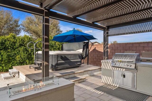 view of patio featuring an outdoor kitchen, area for grilling, an outdoor fire pit, a pergola, and a hot tub