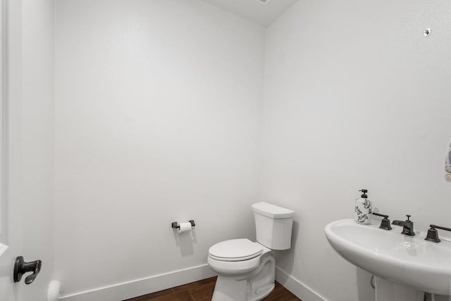 bathroom with toilet, sink, and hardwood / wood-style floors