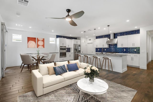 living room featuring dark wood-type flooring, sink, and ceiling fan