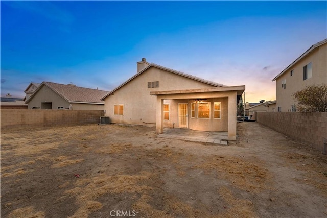 back house at dusk featuring a patio area, ceiling fan, and central AC unit