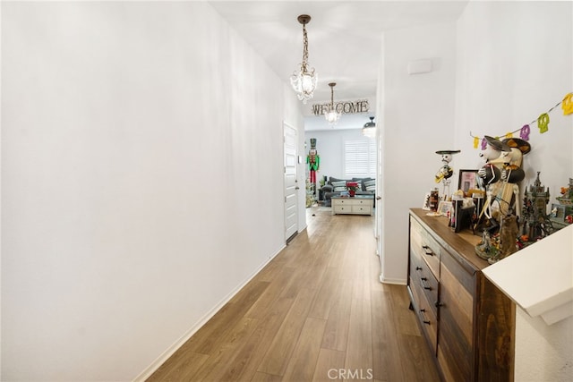 hallway with wood-type flooring and an inviting chandelier