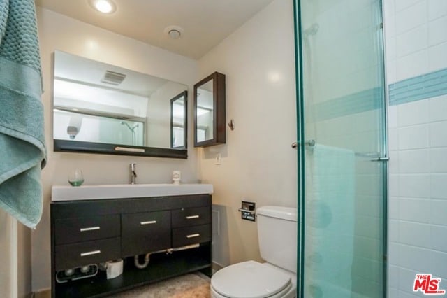 bathroom with vanity, toilet, and a shower with shower door