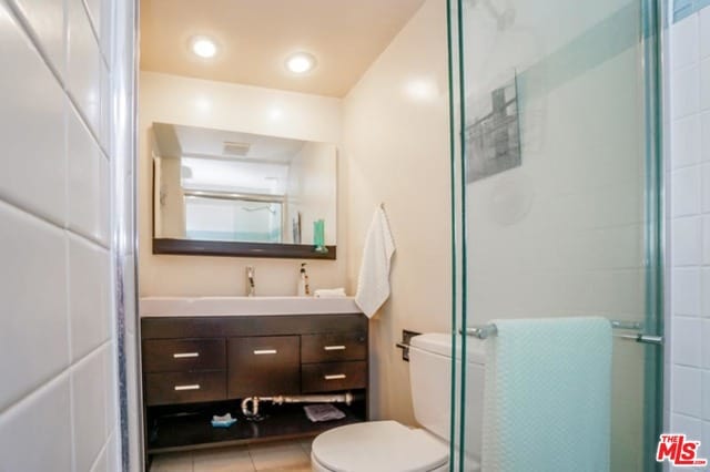 bathroom featuring tile patterned floors, vanity, toilet, and walk in shower