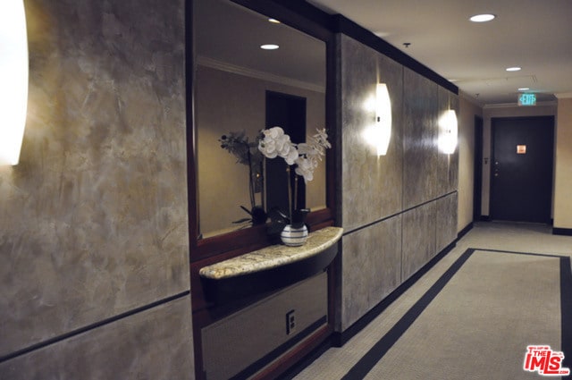 corridor featuring light colored carpet and crown molding