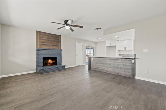 unfurnished living room featuring ceiling fan, a fireplace, and dark hardwood / wood-style floors