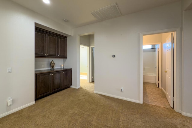 kitchen with dark brown cabinetry and light carpet