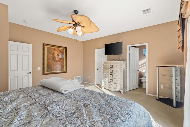 carpeted bedroom with ensuite bath and ceiling fan