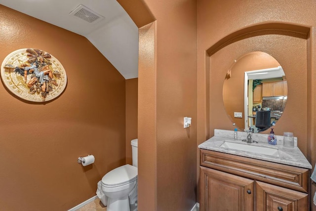 bathroom with vanity, vaulted ceiling, and toilet