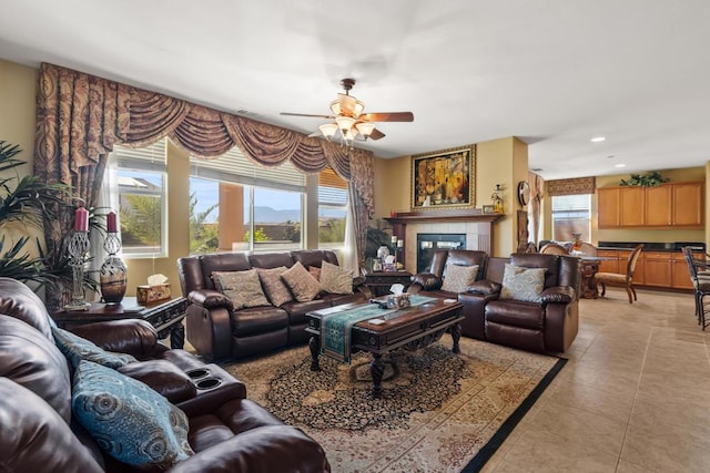 living room with ceiling fan, light tile patterned floors, and a tiled fireplace