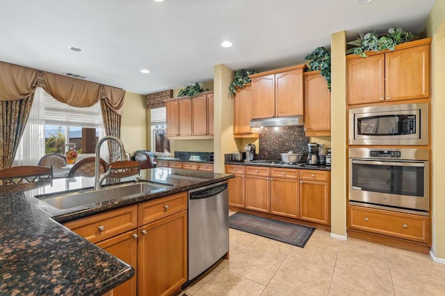 kitchen featuring sink, light tile patterned flooring, dark stone counters, and appliances with stainless steel finishes