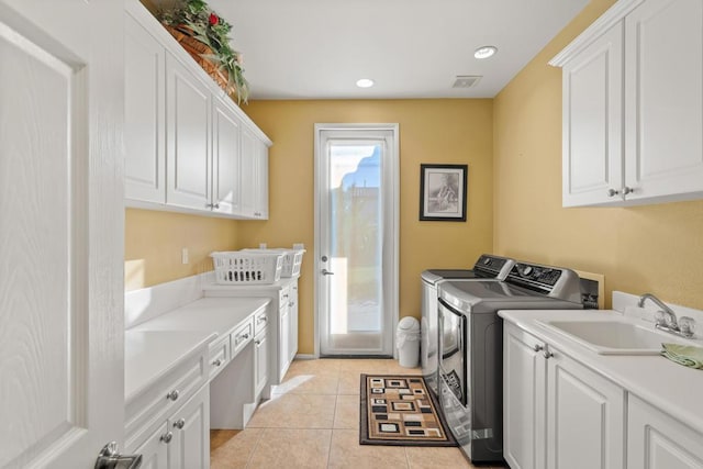 laundry area with light tile patterned flooring, cabinets, separate washer and dryer, and sink