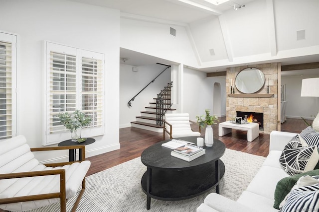 living room with beam ceiling, a stone fireplace, high vaulted ceiling, and dark hardwood / wood-style flooring