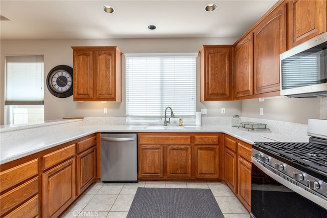 kitchen featuring sink, appliances with stainless steel finishes, kitchen peninsula, and light tile patterned flooring