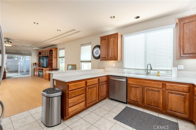 kitchen featuring ceiling fan, stainless steel dishwasher, kitchen peninsula, sink, and light tile patterned floors