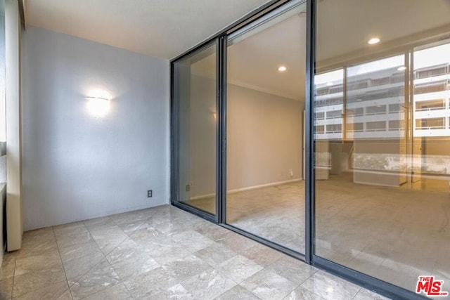 unfurnished bedroom with light carpet, a closet, expansive windows, and crown molding