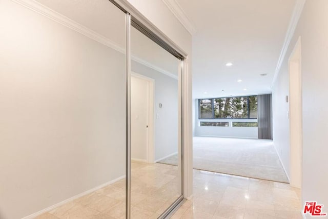 corridor with crown molding and light carpet