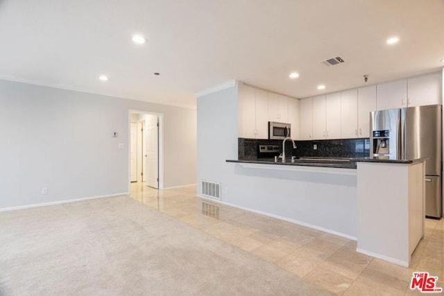 kitchen with tasteful backsplash, white cabinetry, light colored carpet, kitchen peninsula, and stainless steel appliances