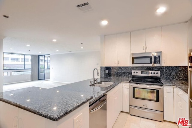 kitchen featuring white cabinets, sink, dark stone countertops, appliances with stainless steel finishes, and kitchen peninsula