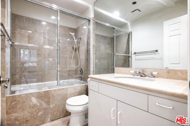 full bathroom featuring toilet, combined bath / shower with glass door, and vanity