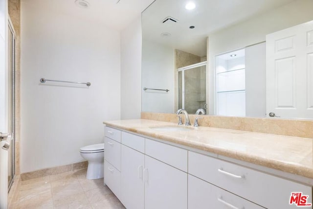 bathroom featuring tile patterned flooring, vanity, toilet, and walk in shower