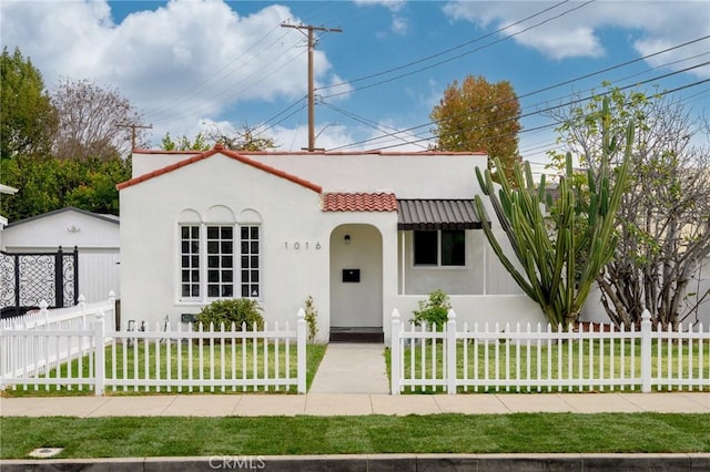 mediterranean / spanish home with a fenced front yard, a front yard, a tile roof, and stucco siding