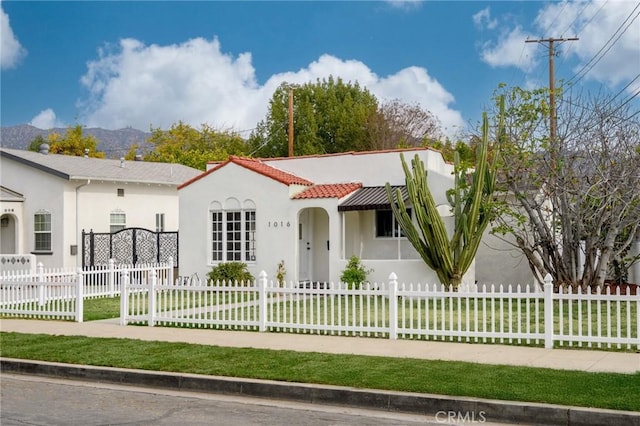 view of front facade with a fenced front yard, a tiled roof, a front lawn, and stucco siding