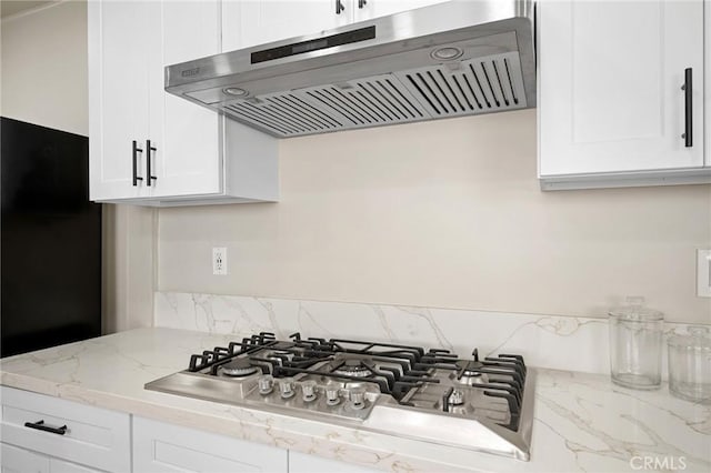 kitchen featuring white cabinetry, stainless steel gas cooktop, under cabinet range hood, and light stone countertops