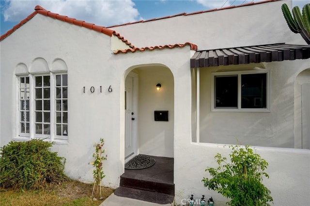 property entrance featuring a tile roof and stucco siding