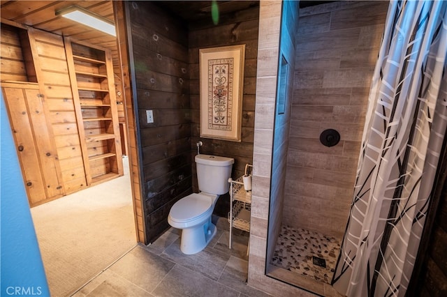 bathroom with wooden walls, a shower with shower curtain, and toilet