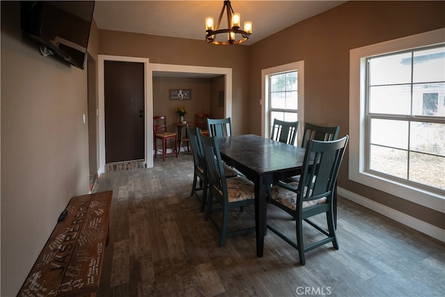 dining area with dark hardwood / wood-style flooring, an inviting chandelier, and plenty of natural light