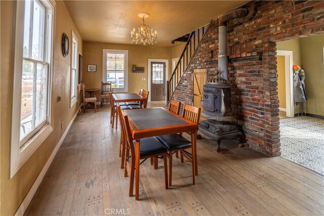 dining room featuring an inviting chandelier, hardwood / wood-style flooring, and a wood stove