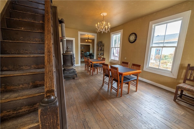 dining space featuring hardwood / wood-style flooring, a wood stove, and an inviting chandelier