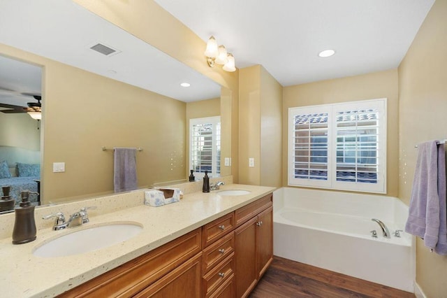 bathroom with hardwood / wood-style flooring, vanity, ceiling fan, and a bathtub