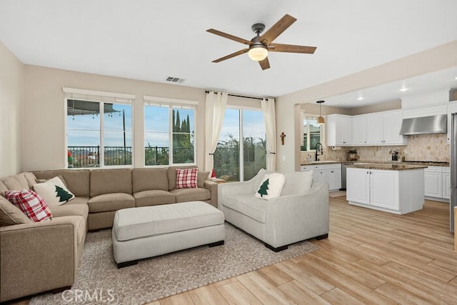 living room featuring sink, light hardwood / wood-style flooring, and ceiling fan