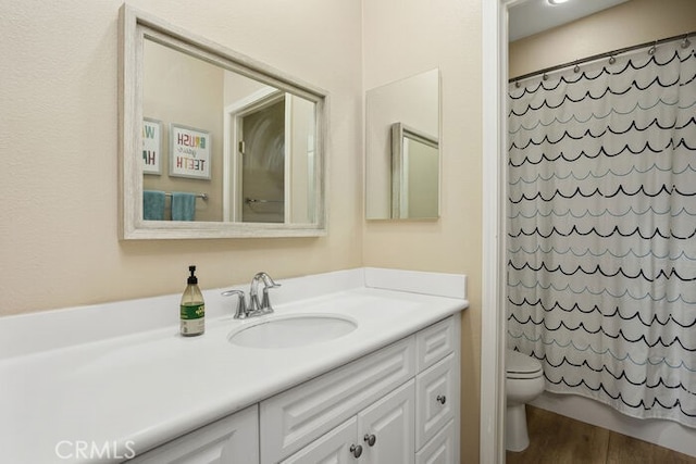 bathroom featuring hardwood / wood-style flooring, vanity, walk in shower, and toilet