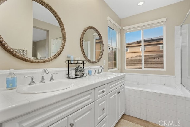 bathroom featuring a relaxing tiled tub and vanity