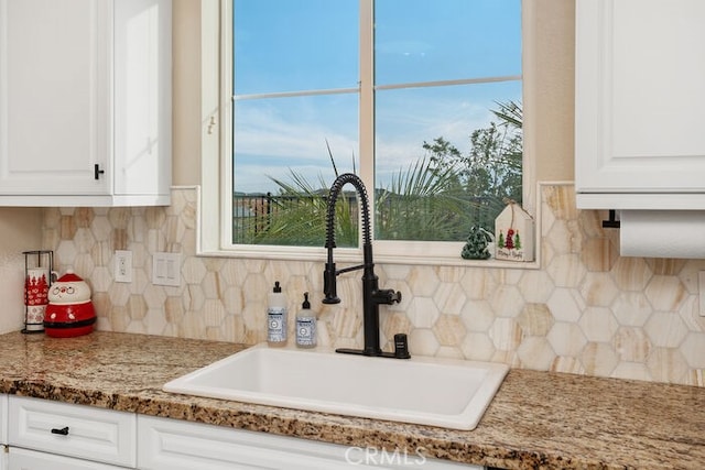 kitchen featuring white cabinetry, sink, tasteful backsplash, and dark stone countertops