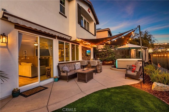 patio terrace at dusk featuring a hot tub and an outdoor hangout area