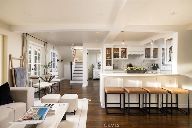 kitchen with beam ceiling, white cabinetry, dark hardwood / wood-style floors, a breakfast bar area, and decorative backsplash