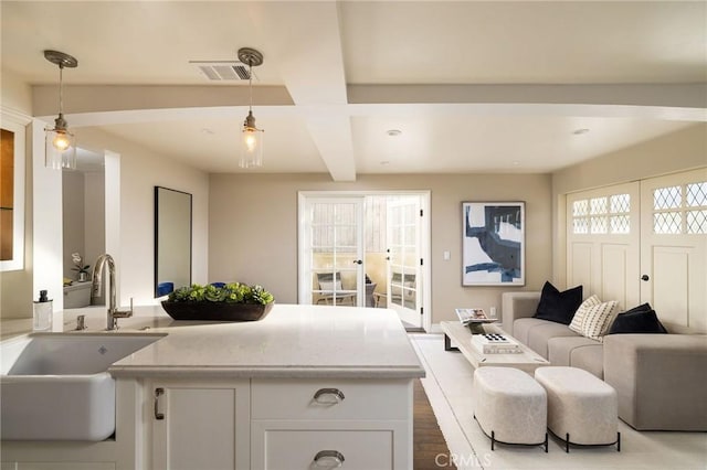 living room with beam ceiling, a healthy amount of sunlight, wood-type flooring, and sink