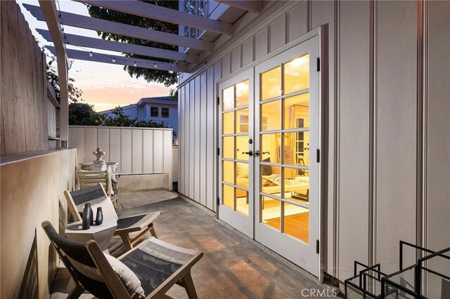 patio terrace at dusk featuring a pergola and french doors