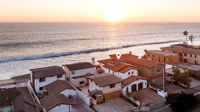 aerial view at dusk featuring a beach view and a water view