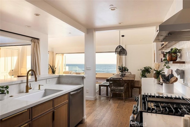 kitchen featuring sink, wall chimney range hood, dark hardwood / wood-style flooring, a water view, and appliances with stainless steel finishes