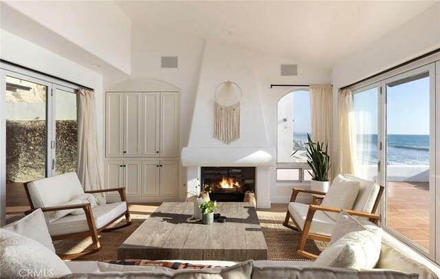 living area with a large fireplace, a water view, and vaulted ceiling