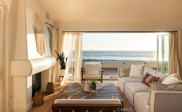 sitting room with a water view, wood-type flooring, and a beach view