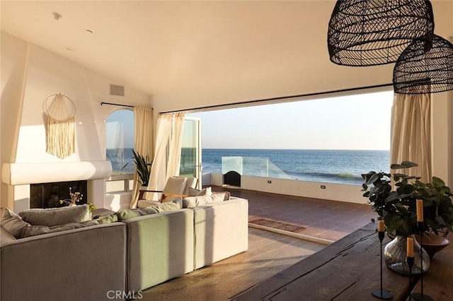 living room with hardwood / wood-style flooring, a water view, lofted ceiling, and a fireplace